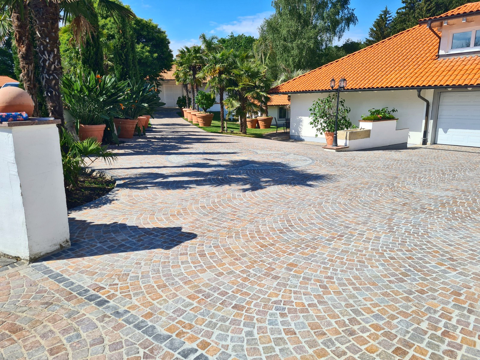 Geschwungene Natursteinpflaster-Einfahrt mit Palmen und mediterranem Flair