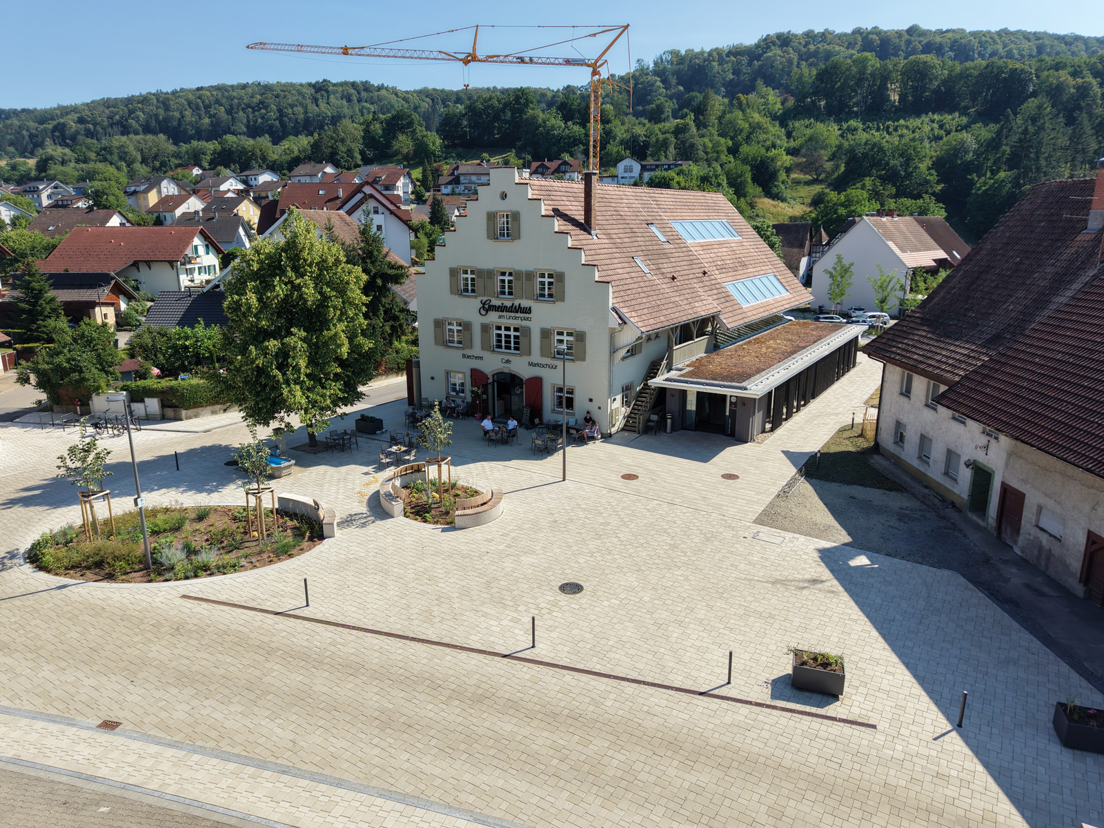 Luftaufnahme eines neu gestalteten Dorfplatzes mit Gasthaus