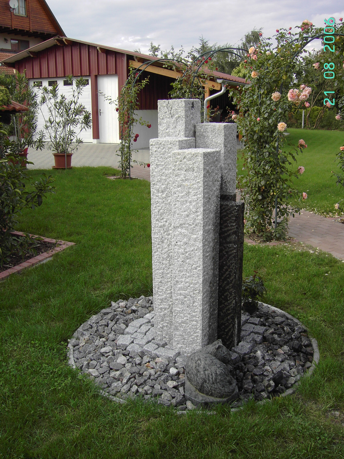 Granitstelen-Brunnen im Kiesbett