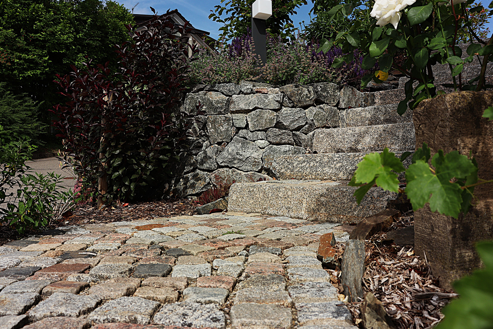 Natursteinmauer mit Sitzplatz aus Altpflaster
