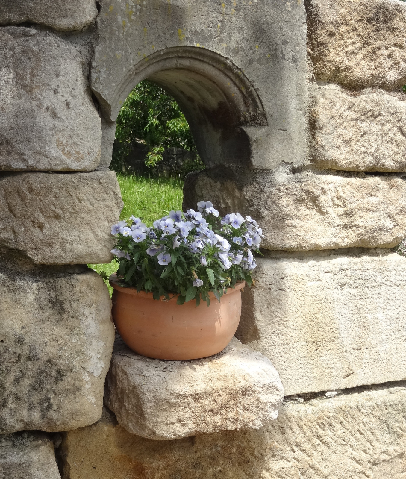 Nische in Natursteinmauer mit Blumentopf
