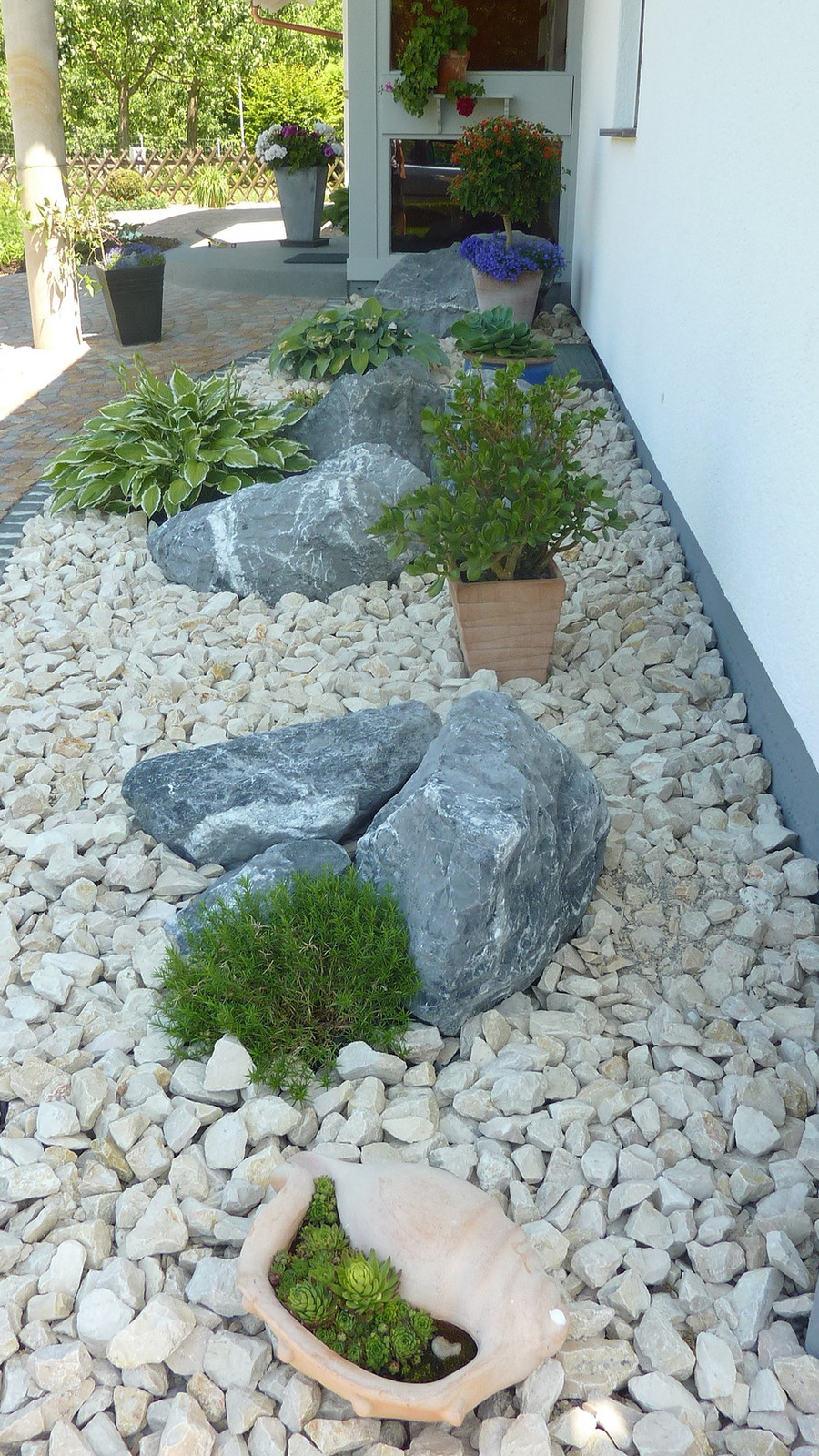 Schmaler Steingarten mit Findlingen und Kies am Haus