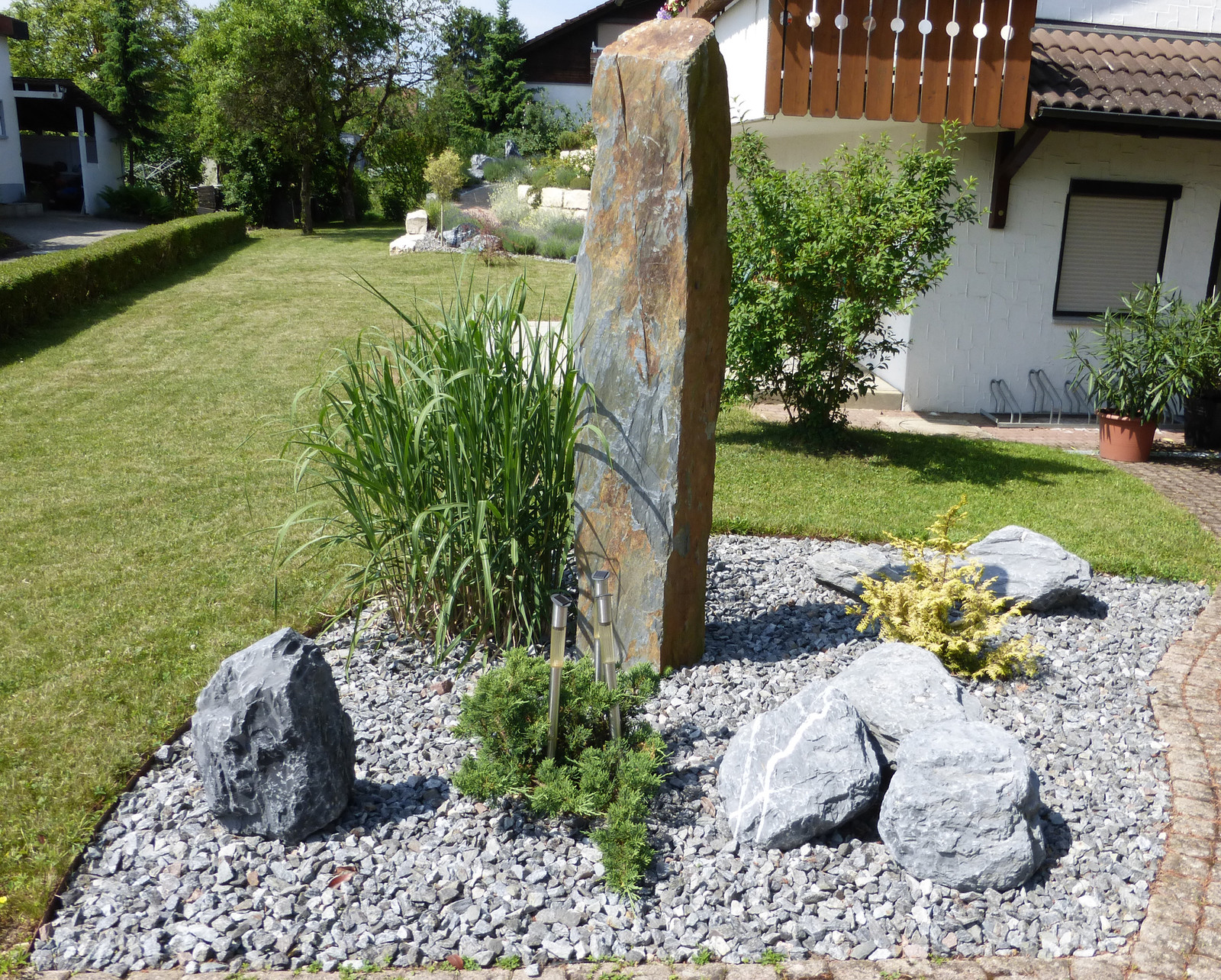 Steingarten mit Natursteinstele und Gräsern