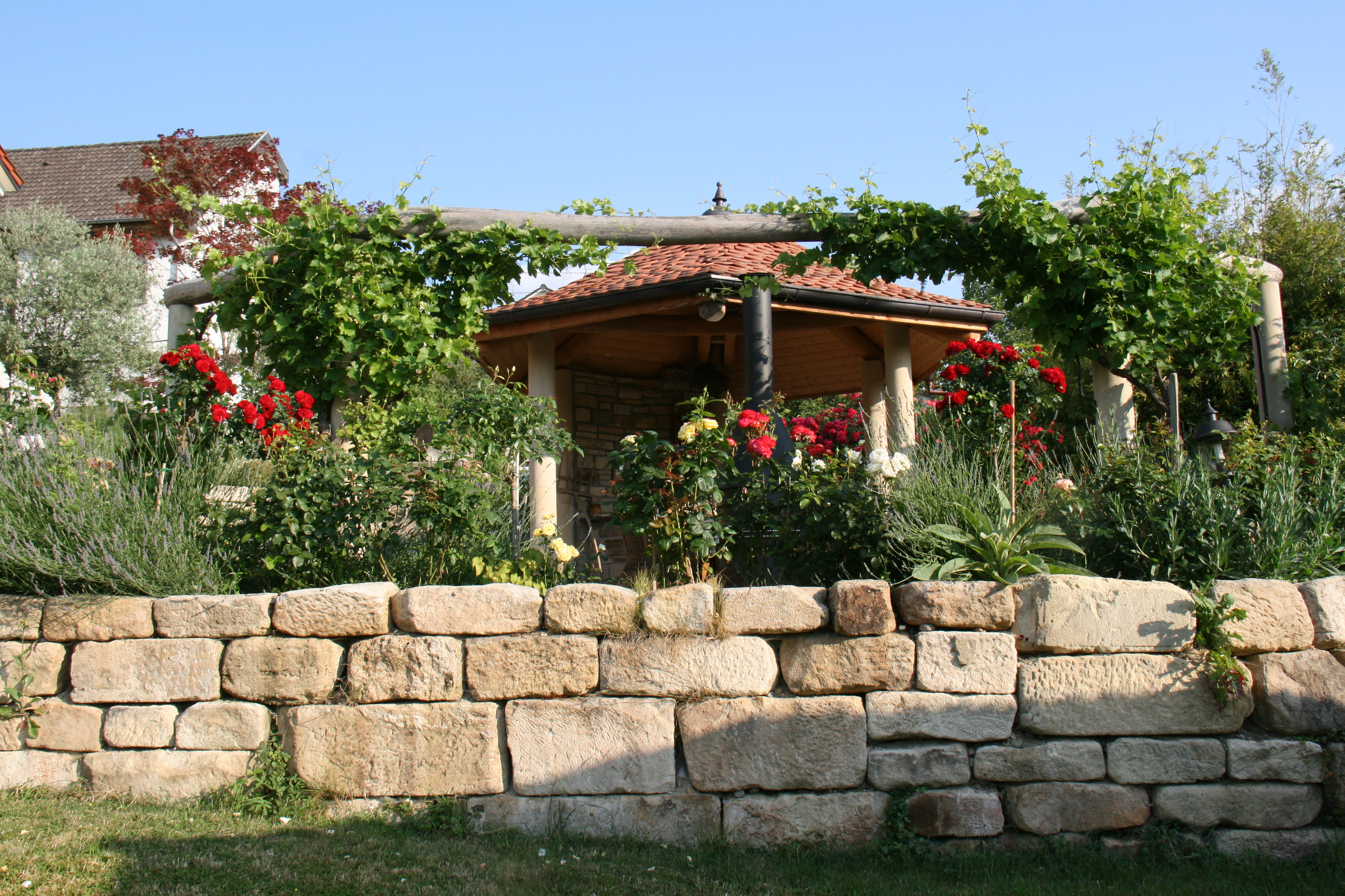 Natursteinmauer mit Pavillon und Rosen