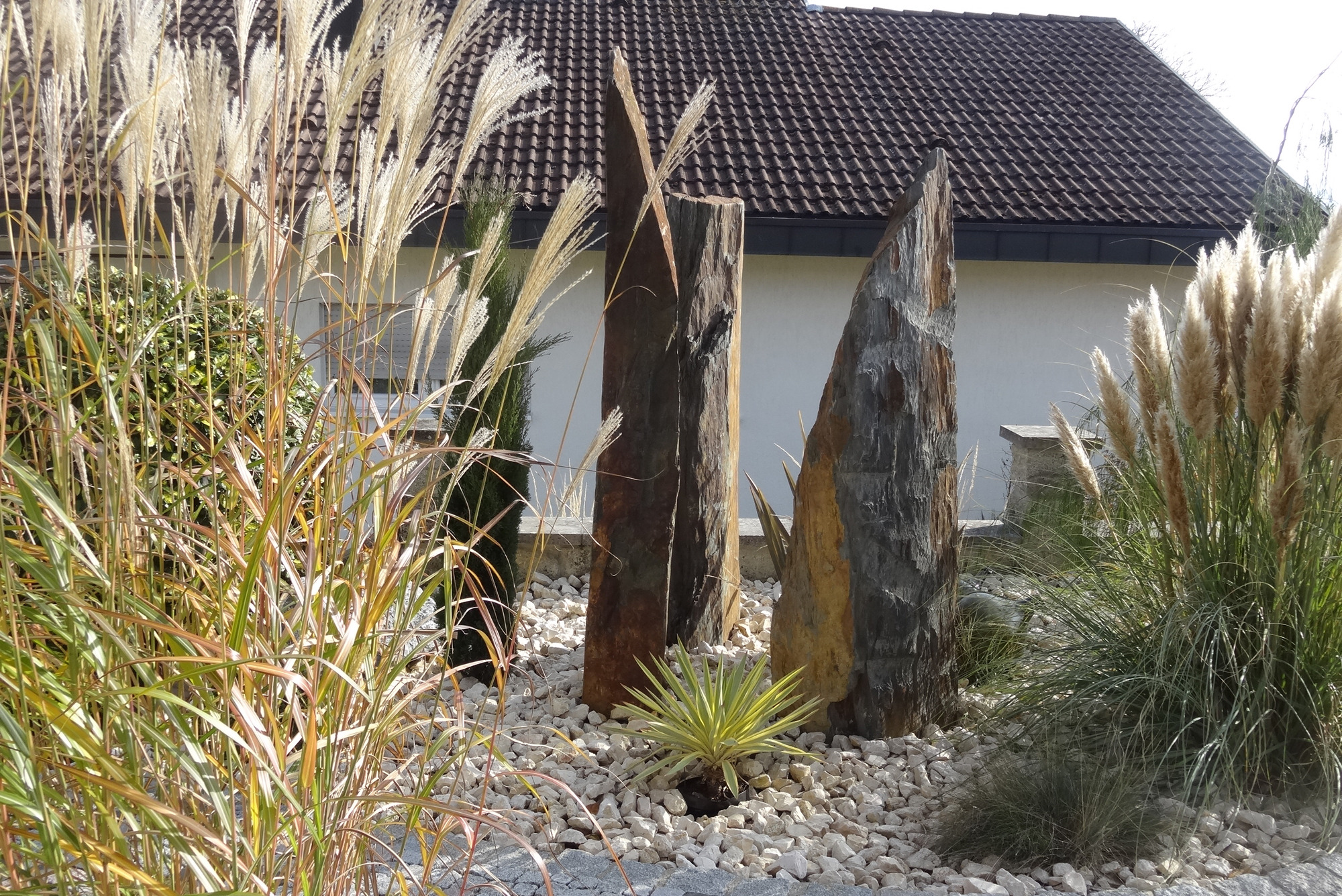 Stelen mit Gräsern im Steingarten